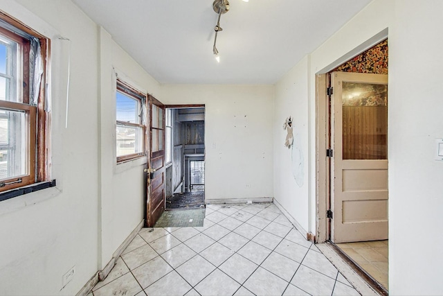 interior space featuring plenty of natural light, light tile patterned floors, and rail lighting