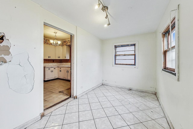 unfurnished room featuring a notable chandelier and rail lighting