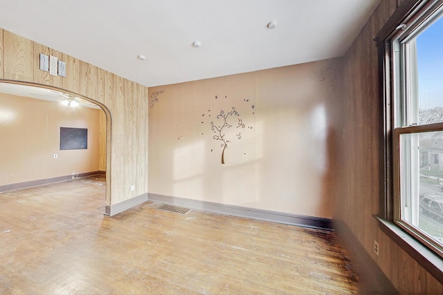 spare room with a wealth of natural light and wood walls