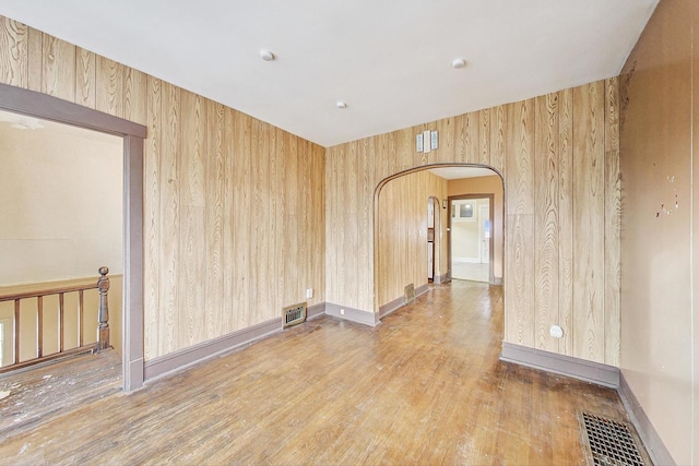 spare room with hardwood / wood-style flooring and wooden walls