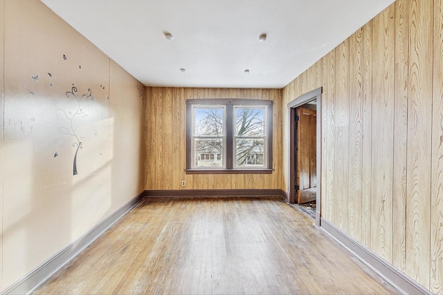 unfurnished room featuring wood walls and light wood-type flooring