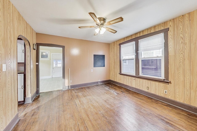 unfurnished room with hardwood / wood-style flooring, ceiling fan, and wood walls