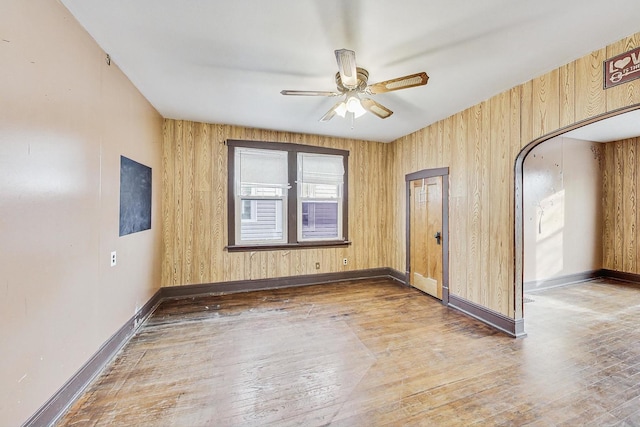 spare room with hardwood / wood-style flooring, ceiling fan, and wooden walls