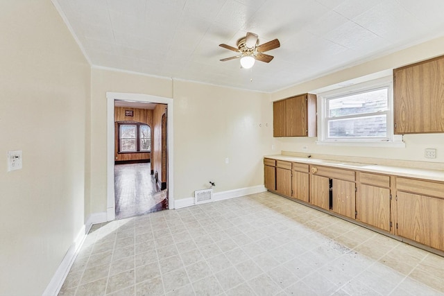 kitchen featuring ceiling fan, crown molding, and sink