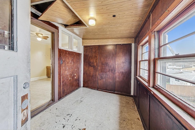 empty room with ceiling fan, wood walls, and wooden ceiling