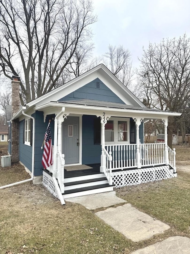 view of front of home featuring a porch, a front yard, and cooling unit