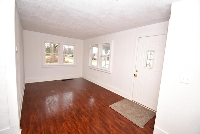 foyer entrance featuring a textured ceiling and dark wood-type flooring