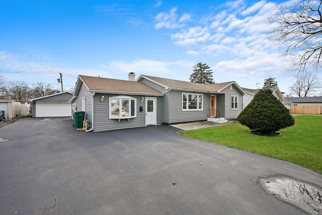 single story home with a garage, an outdoor structure, and a front lawn