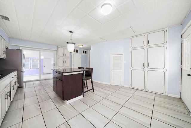 kitchen featuring decorative light fixtures, white cabinetry, a kitchen island, and a breakfast bar area