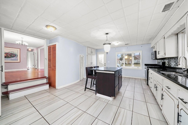 kitchen with pendant lighting, a center island, white cabinets, appliances with stainless steel finishes, and a kitchen bar