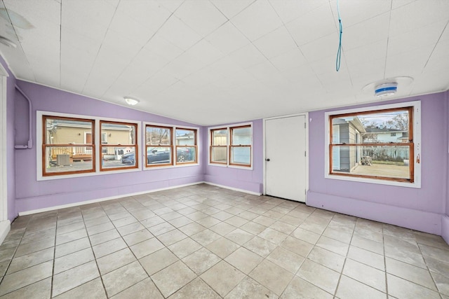 tiled spare room featuring vaulted ceiling