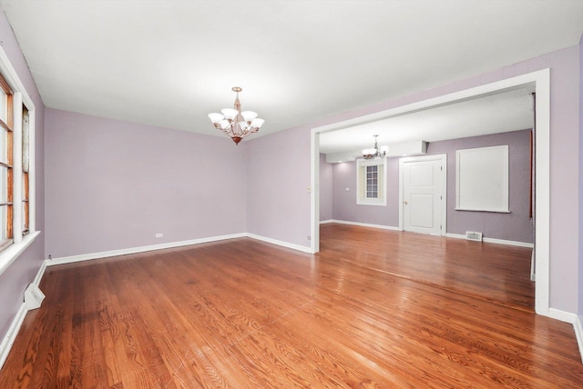 spare room featuring hardwood / wood-style floors, an inviting chandelier, and a wealth of natural light