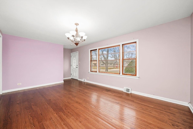 unfurnished room featuring a chandelier and dark wood-type flooring