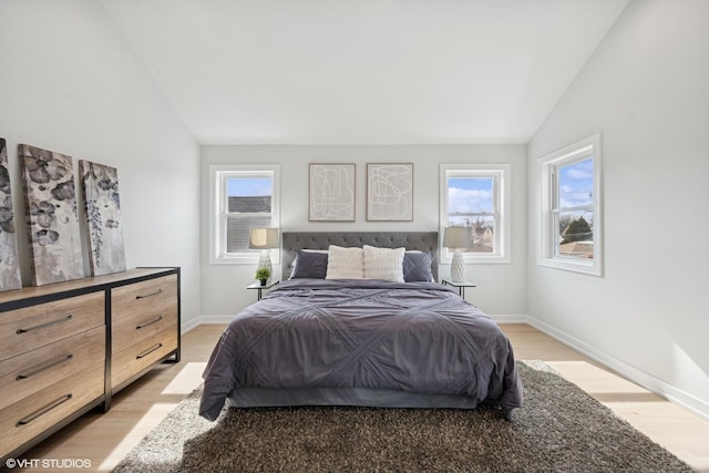 bedroom featuring baseboards, vaulted ceiling, and light wood finished floors