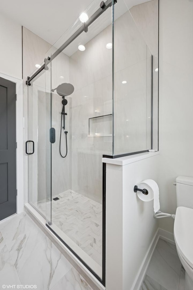 bathroom featuring marble finish floor, a shower stall, toilet, and baseboards