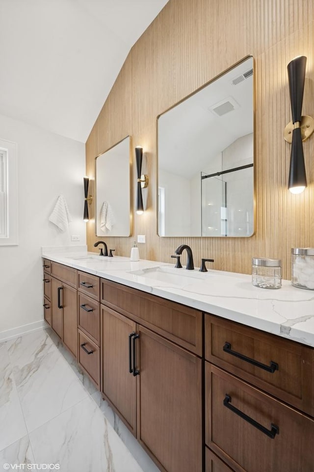 full bath featuring lofted ceiling, marble finish floor, a sink, and double vanity