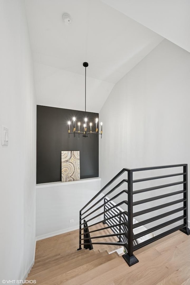 staircase with lofted ceiling, baseboards, wood finished floors, and a chandelier