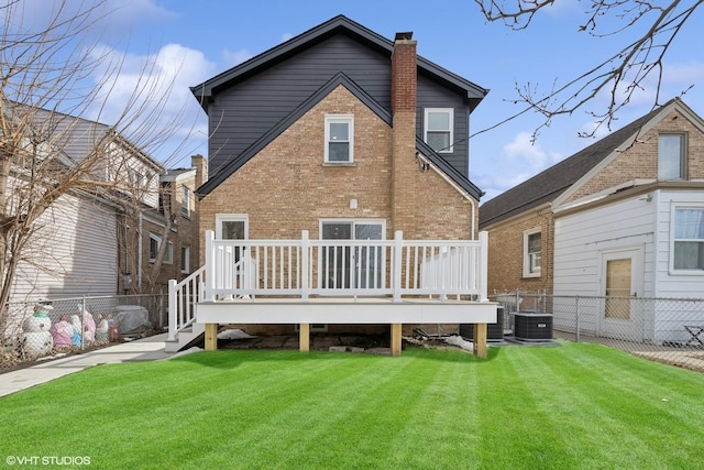 back of house with a chimney, fence, a lawn, and brick siding