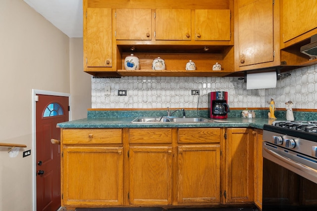 kitchen featuring decorative backsplash, stainless steel gas range oven, and sink