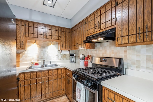 kitchen featuring light countertops, brown cabinetry, stainless steel range with gas cooktop, and under cabinet range hood