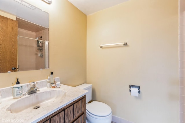 bathroom featuring toilet, a shower stall, and vanity