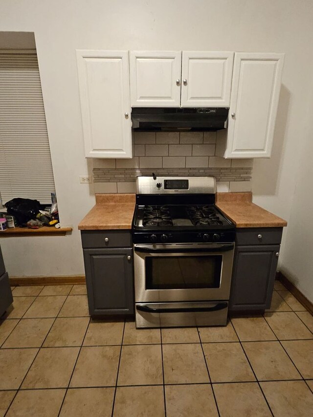 kitchen featuring tasteful backsplash, stainless steel range with gas cooktop, white cabinets, and light tile patterned flooring