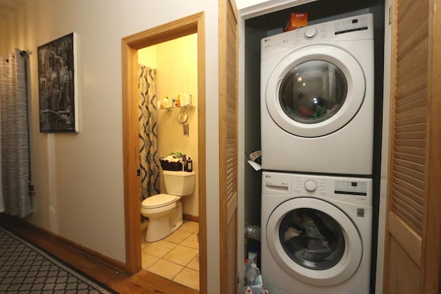 laundry room featuring stacked washer and dryer and light tile patterned floors