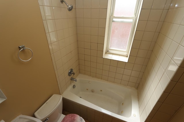 bathroom with toilet and tiled shower / bath