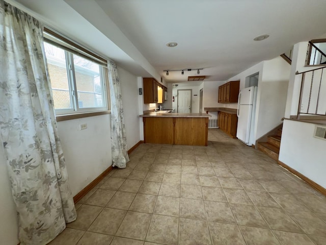 kitchen with white fridge, light tile patterned flooring, kitchen peninsula, and track lighting