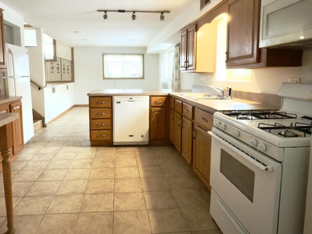 kitchen with kitchen peninsula, light tile patterned floors, white appliances, and sink