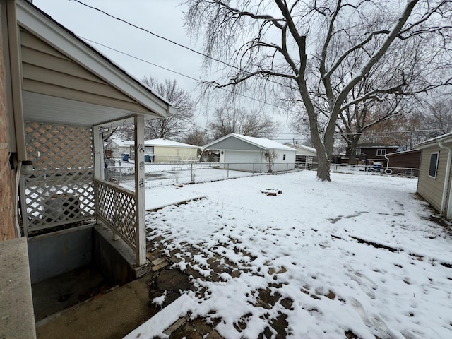 snowy yard featuring a garage and an outbuilding