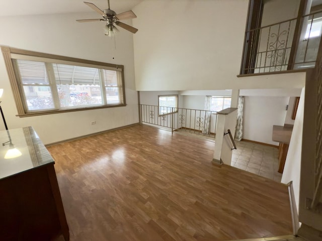 unfurnished living room featuring ceiling fan, wood-type flooring, and high vaulted ceiling