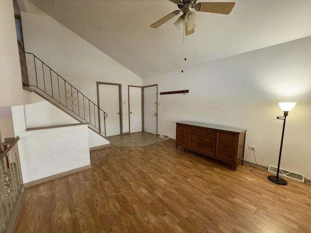 unfurnished living room with ceiling fan, light wood-type flooring, and high vaulted ceiling