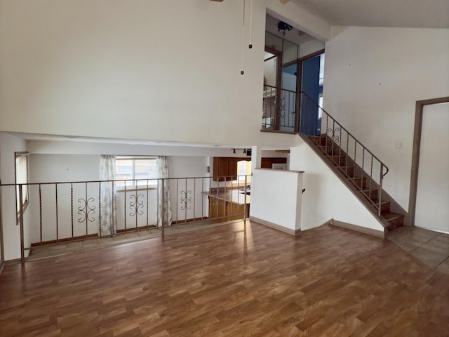 unfurnished living room featuring ceiling fan, high vaulted ceiling, and hardwood / wood-style flooring