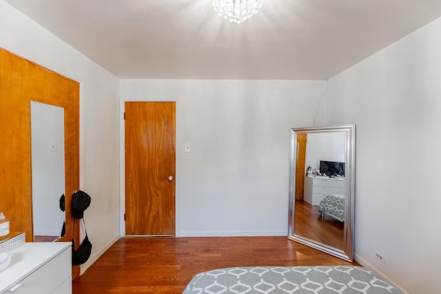 unfurnished bedroom with a closet, a notable chandelier, and hardwood / wood-style flooring