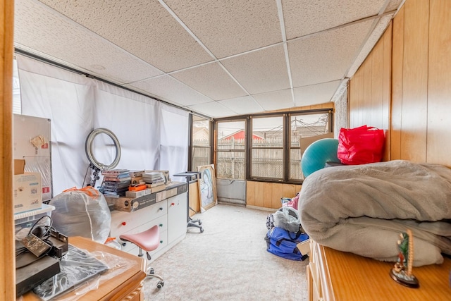 bedroom with a paneled ceiling, wooden walls, and carpet floors