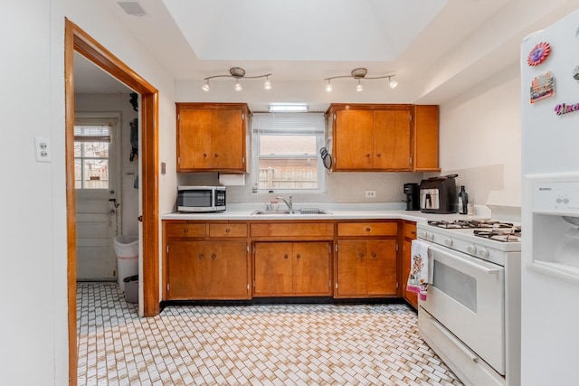 kitchen with decorative backsplash, white appliances, a healthy amount of sunlight, and sink