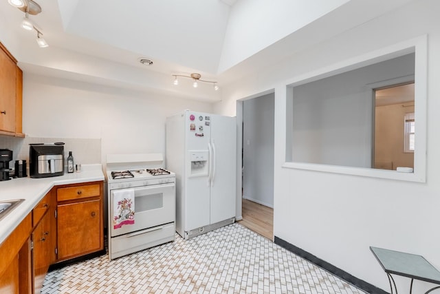 kitchen featuring white appliances, track lighting, vaulted ceiling, and backsplash