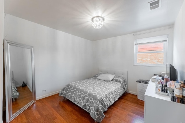 bedroom featuring wood-type flooring and a chandelier