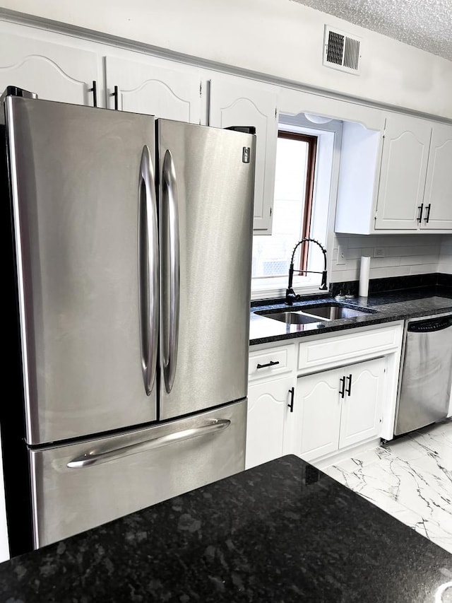 kitchen with backsplash, sink, a textured ceiling, appliances with stainless steel finishes, and white cabinetry