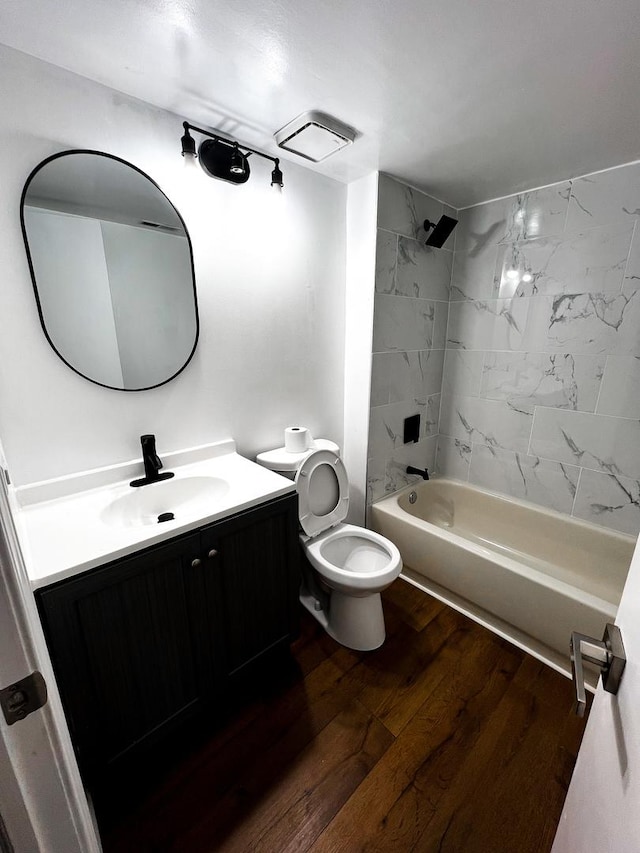 full bathroom with hardwood / wood-style floors, tiled shower / bath combo, toilet, and vanity