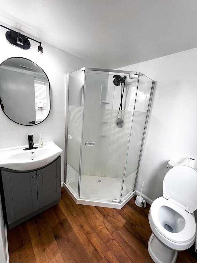 bathroom featuring hardwood / wood-style floors, vanity, toilet, and walk in shower