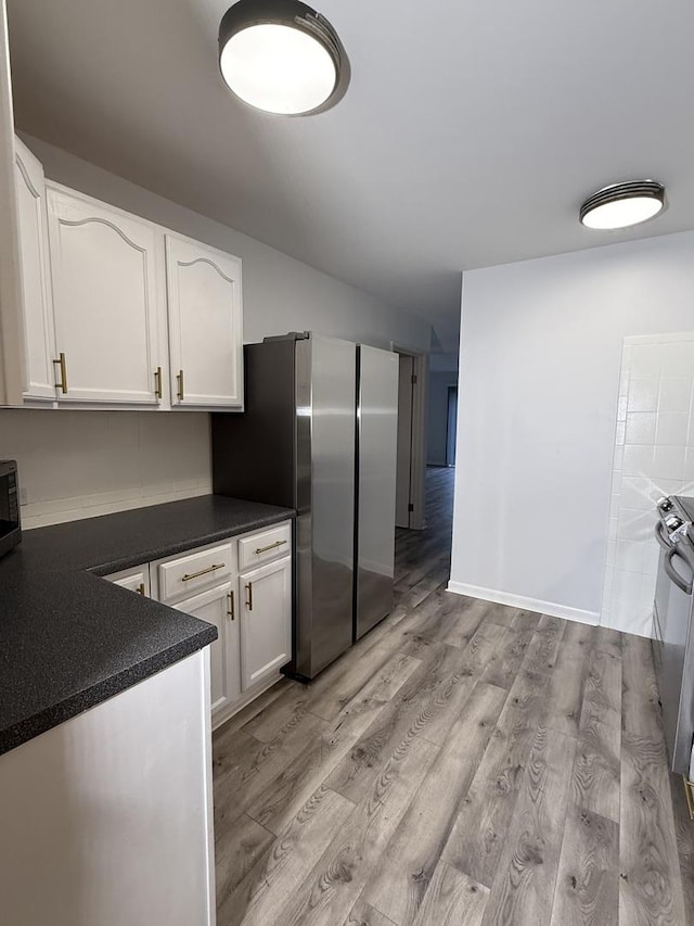 kitchen with light wood-type flooring, stainless steel appliances, and white cabinetry