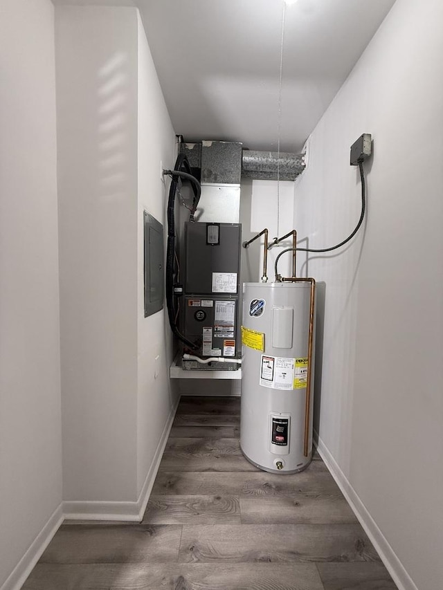 utility room with electric panel, water heater, and heating unit