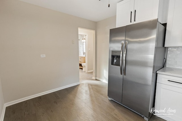 kitchen with stainless steel fridge, dark hardwood / wood-style flooring, and white cabinetry