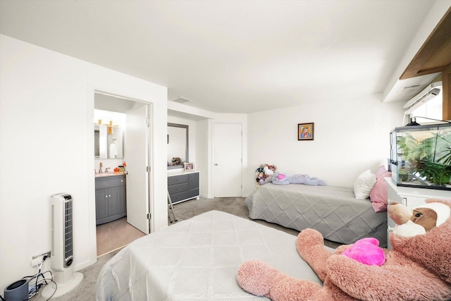 bedroom with ensuite bathroom and light colored carpet