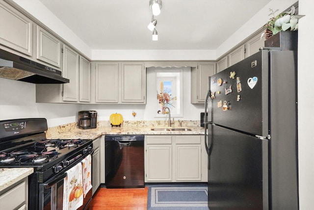 kitchen with black appliances, gray cabinetry, light wood-type flooring, and sink