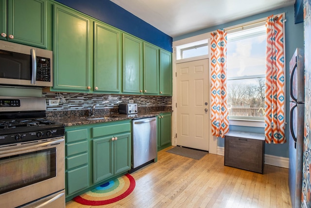 kitchen featuring dark stone counters, green cabinets, plenty of natural light, and stainless steel appliances