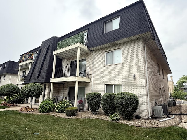 10936 Kilpatrick Ave Unit 1B, Oak Lawn, IL 60453 - rear view of house with brick siding, a balcony, a lawn, and mansard roof