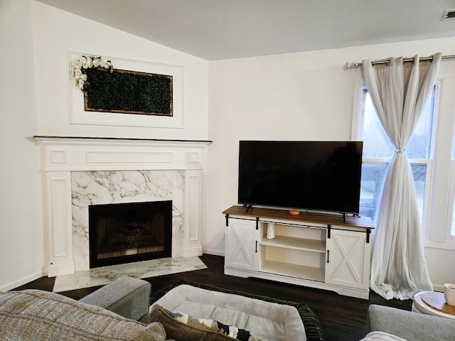 living room featuring a high end fireplace, lofted ceiling, and dark wood-type flooring